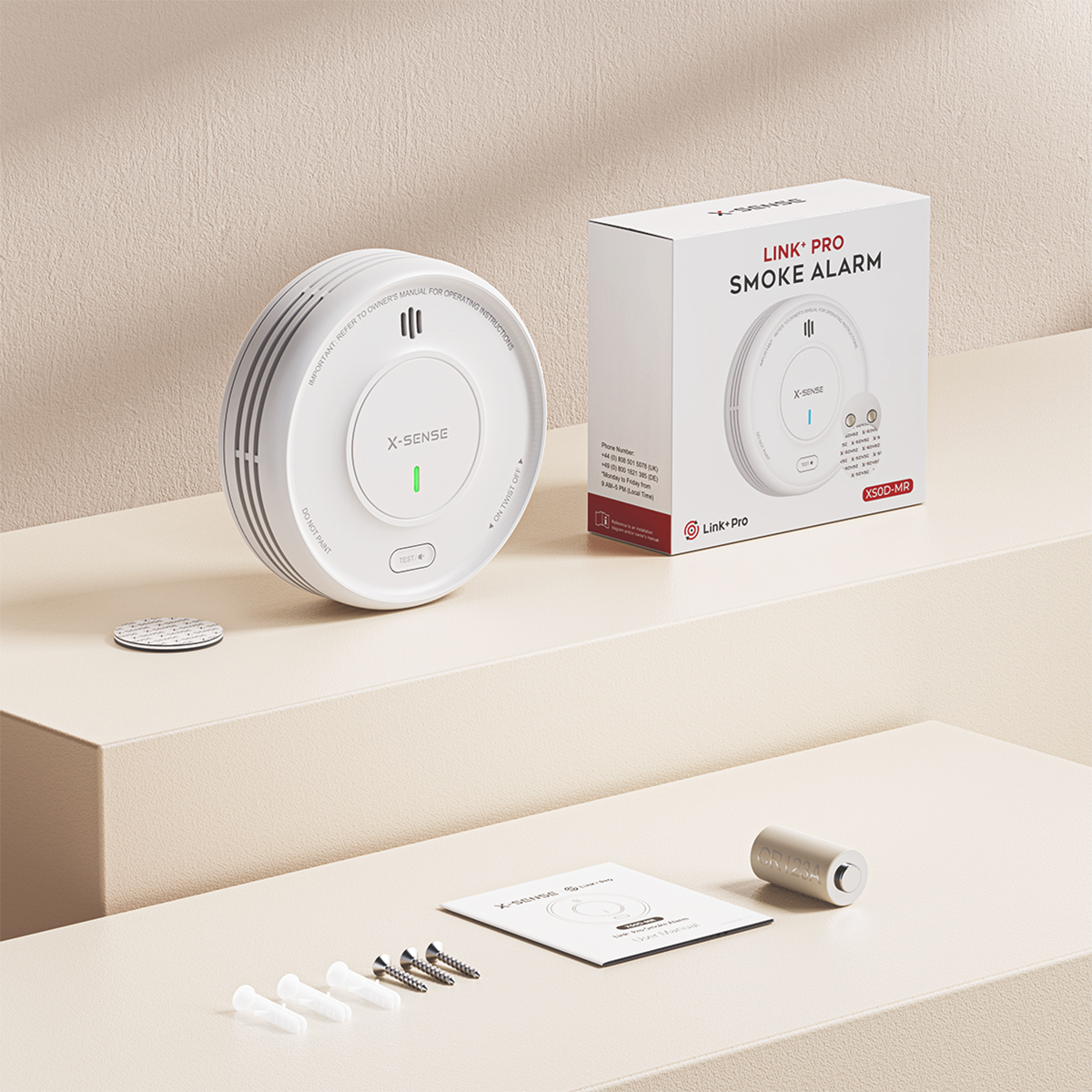 Förpackning med rökvarnare XS0D och dess innehåll, skruvar, tejp och manual